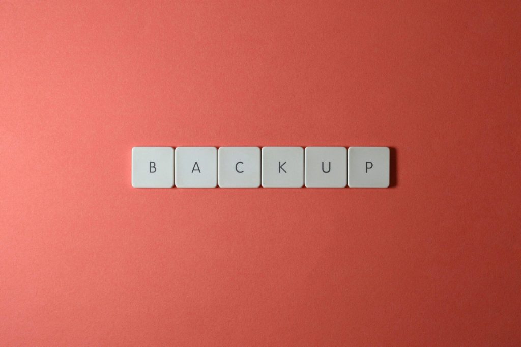 Free Close-up of keyboard keys spelling 'BACKUP' placed on a coral-colored surface. Stock Photo